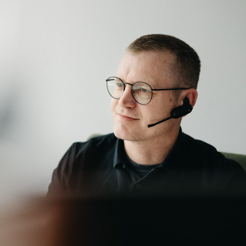 Freundlicher Mann mit Brille und Headset, konzentriert auf die Arbeit. Karriere.