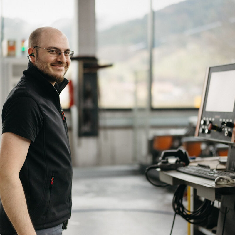 Glücklicher männlicher Mitarbeiter in einem Produktionsumfeld. Karriere