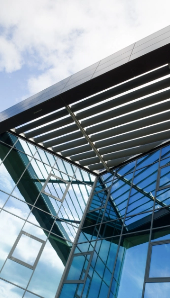 Modernes Glasgebäude mit geometrischem Design und Lamellendach