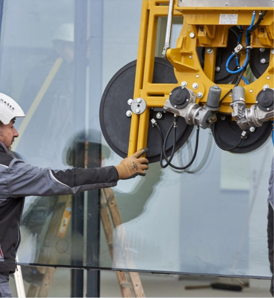 Arbeiter verwendet einen Vakuumheber zum Einbau einer großen Glasplatte.