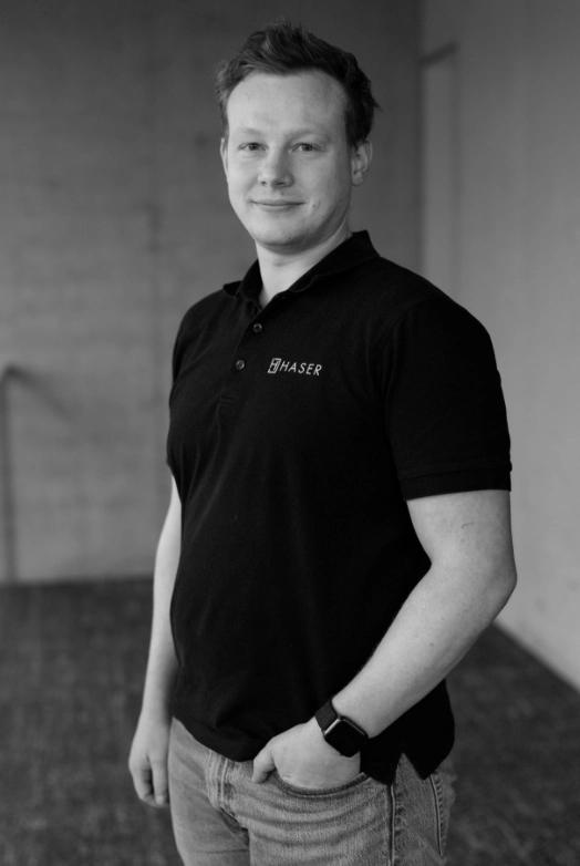 http://Porträt%20eines%20Mannes,%20der%20ein%20schwarzes%20Haser-Poloshirt%20trägt.