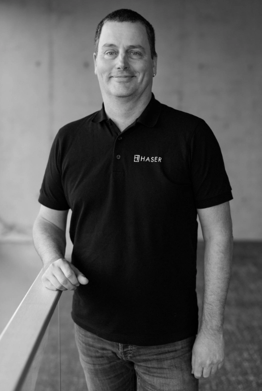 http://Porträt%20eines%20Mannes,%20der%20ein%20schwarzes%20Haser-Poloshirt%20trägt.