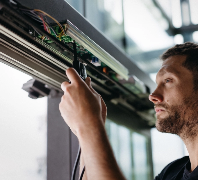Techniker repariert automatische Türsysteme. Metallbearbeitungsdienstleistungen.