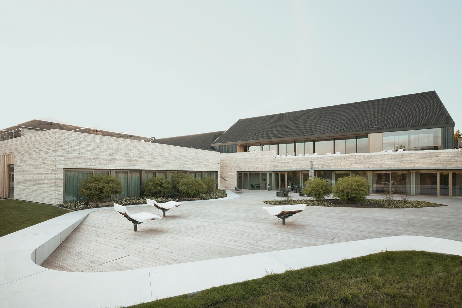 Modernes Spa-Exterieur mit heller Steinfassade und Loungebereich im Freien.